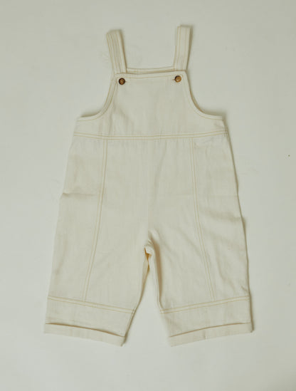 Stylish and comfortable kids' overalls in a cream color featuring a relaxed fit, adjustable straps, and durable organic cotton twill fabric. 