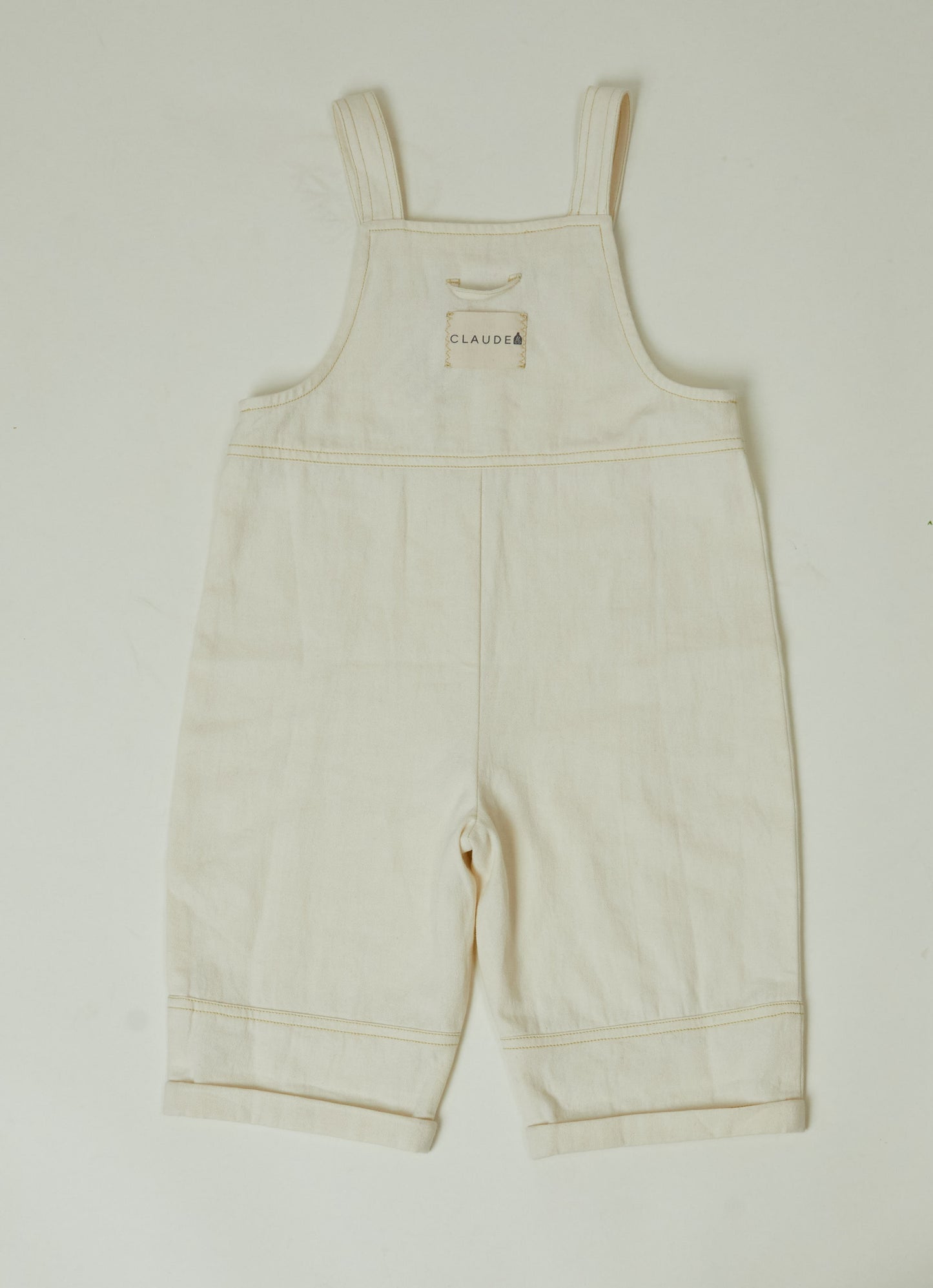 Stylish and comfortable kids' overalls in a cream color featuring a relaxed fit, adjustable straps, and durable organic cotton twill fabric. 