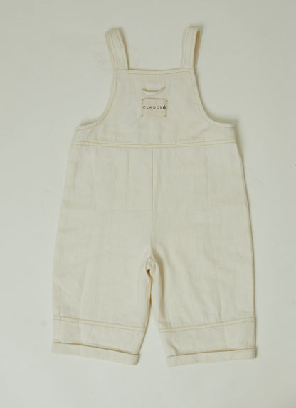 Stylish and comfortable kids' overalls in a cream color featuring a relaxed fit, adjustable straps, and durable organic cotton twill fabric. 