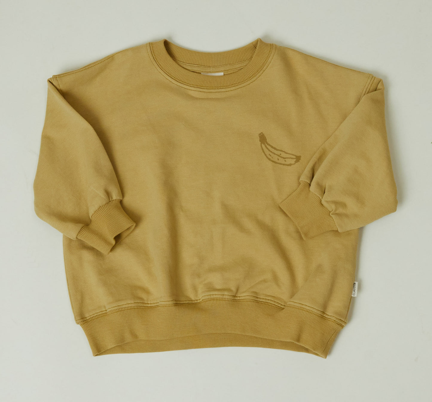 Jesse Sweater in a tonal mustard yellow featuring a banana image on front chest and a fun Claude & Co. breakfast slogan on the back.